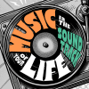 An olive green t-shirt featuring a vintage turntable graphic with a vinyl record. The text "MUSIC IS THE SOUNDTRACK OF YOUR LIFE" is integrated into the record design in orange, teal, and white retro lettering. Part of the Dare To Live Vibe collection.